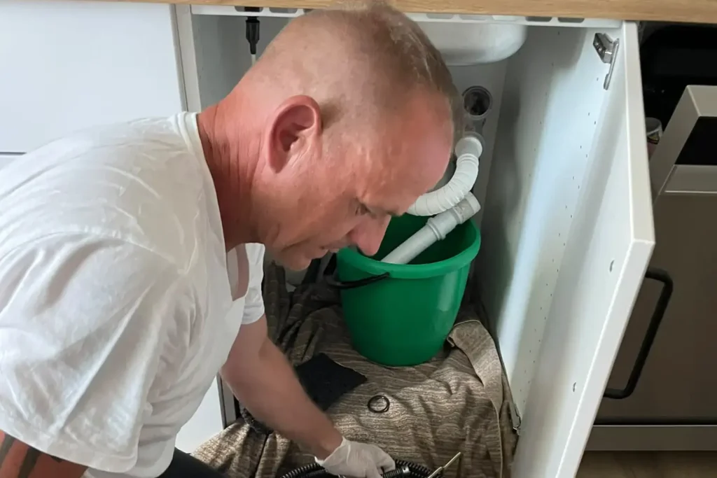 Marc Besler udrażnia zapchany odpływ pod zlewem kuchennym